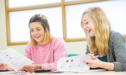 Two female students smiling at their papers