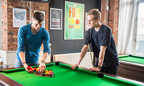 Two male students enjoying a game of pool in the student union